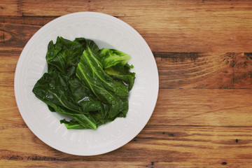 boiled cabbage on white plate on brown wooden background