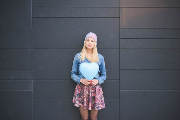 Knee figure of young beautiful blonde girl posing leaning on a w