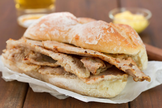 bread with meat on brown wooden background and glass of beer