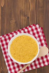 pasta on white bowl on napkin on brown wooden background