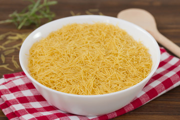 pasta on white bowl on napkin on brown wooden background