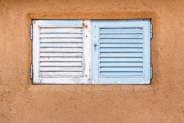 Wooden window embedded in a mud and clay wall.