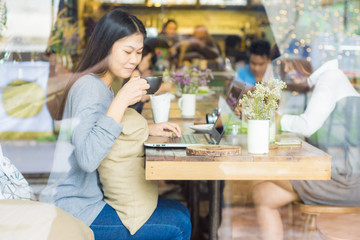 smiling asian women work on laptop at cafe