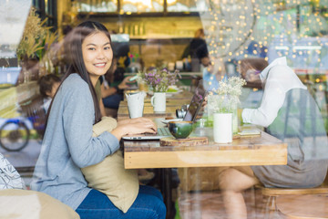 Asian woman using laptop with latte art coffee