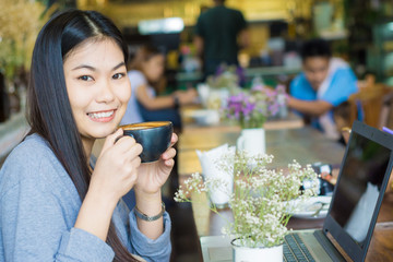 smiling asian women work on laptop at cafe