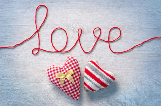 Word "love" and two hearts on white wooden background. View from above. Valentines Day concept