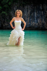 Fototapeta na wymiar blonde bride in fluffy hands on waist in shallow azure sea