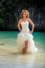 Fototapeta na wymiar blonde bride in fluffy hands on waist in shallow azure sea