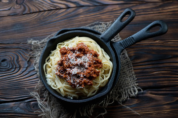 Frying pan with spaghetti bolognese in a rustic wooden setting