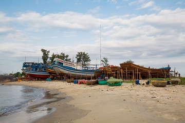 Fototapeta na wymiar Strand mit Fischerbooten und Werft in Phan Thiet Vietnam