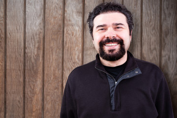 Smiling Bearded Man Against Wooden Wall