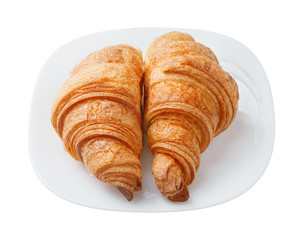 .Two fresh croissant on a white plate.