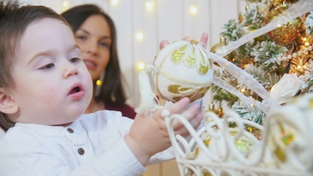 Family decorating a Christmas tree with boubles in the living-room