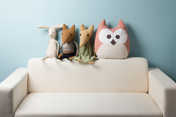 Home interior. Childhood. Blue background. Toy sitting on a couch. Copy space.