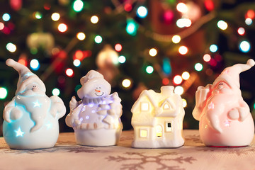 Illuminated Snowman, Christmas house  and Jack Frost (Santa Claus) toys in front of Christmas tree lights that are defocused, blurred background
