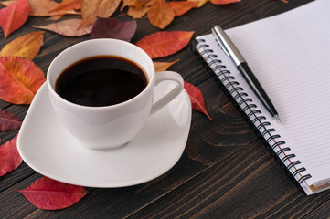 American cup of coffee with autumn leaves, notebook and pen