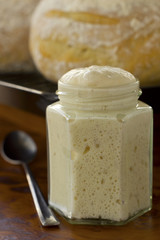 Sourdough starter fermenting and starts to be ripen. Sourdough bread in background. Non Sharpen