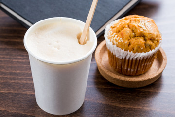 cup of coffee and fresh muffin on wooden table with drawing