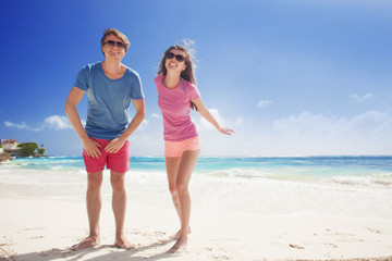 couple in bright clothes enjoying sunny day at tropical beach