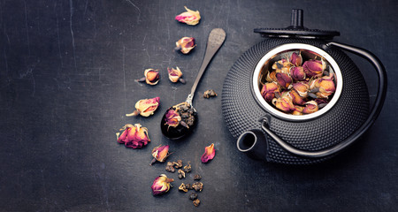 Green tea with flowers roses in cast-iron kettle. Asian style