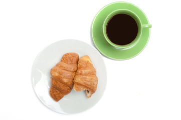 Two croissants on white plate and black coffee in green cup, top