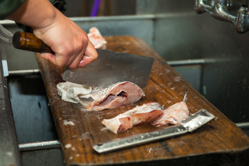 close-up of a worker cutting fish on a board at the restaurant kitchen