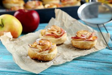 Fresh puff pastry with apple shaped roses on blue wooden table