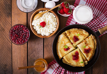 Golden pancakes with cranberry jam and honey in a rustic style. Top view