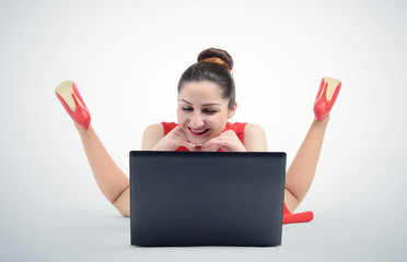 Happy woman in red dress lying and working with a laptop