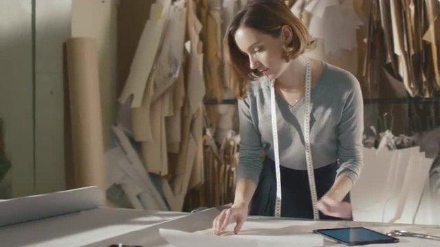 Clothing designer is working with a tablet in a workshop. Shot on RED Cinema Camera.
