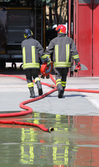 two firefighters carry the hydrant and hose pipes