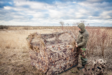 Man installing hunting tent in rural field    © splendens