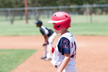 Young american baseball boy on first base