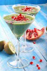 Fresh healthy kiwi drink with pomegranate on wooden blue backgro