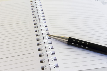 primo piano di biro e agenda calendario su scrivania d'ufficio