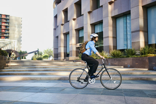 Caucasian businessman riding bicycle outside office building