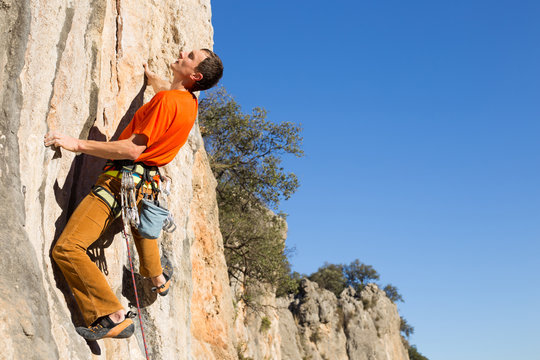 Young male rock climber on challenging route on cliff.
