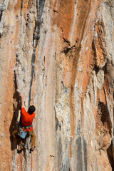 Fototapeta premium Young male rock climber on challenging route on cliff.