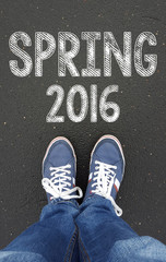 male legs in sneakers on the asphalt road with spring 2016 sign