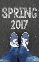 male legs in sneakers on the asphalt road with spring 2017 sign