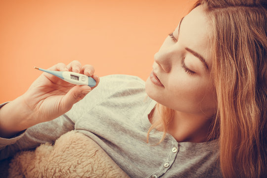 Sick ill woman with digital thermometer.