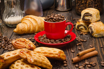 Cup of Coffee Beans with Pastry on brown wood table background