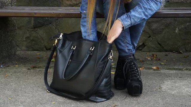 Woman looking for something in her handbag 4K