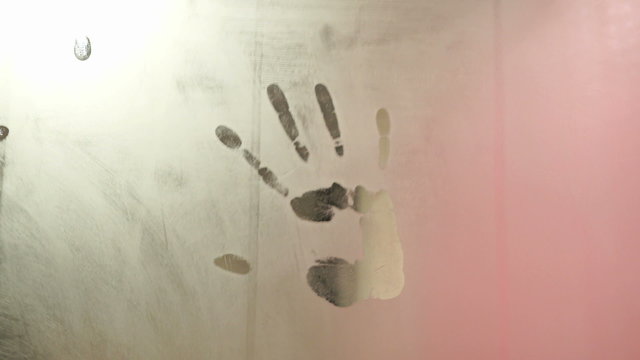 girl puts her handprint on a foggy mirror