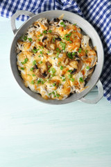 Roasted mushrooms, chicken and cheese gratin in pan, on wooden background