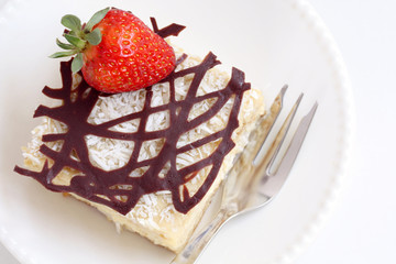 isolated slice of decorated with chocolate and strawberry napoleon cake, served on white plate