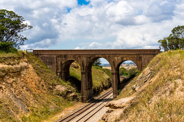 Fototapeta na wymiar Picturesque old arch bridge, viaduct with railway underneath. Ta