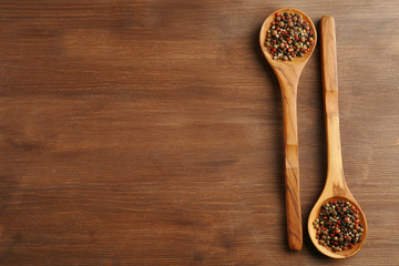 Two wooden spoons with pepper on the table, close-up