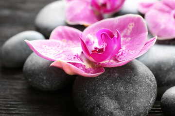 Spa stones and orchids on wooden background
