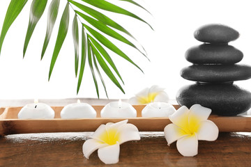 Obraz na płótnie Canvas Spa stones with candles, plumeria and bamboo, isolated on white